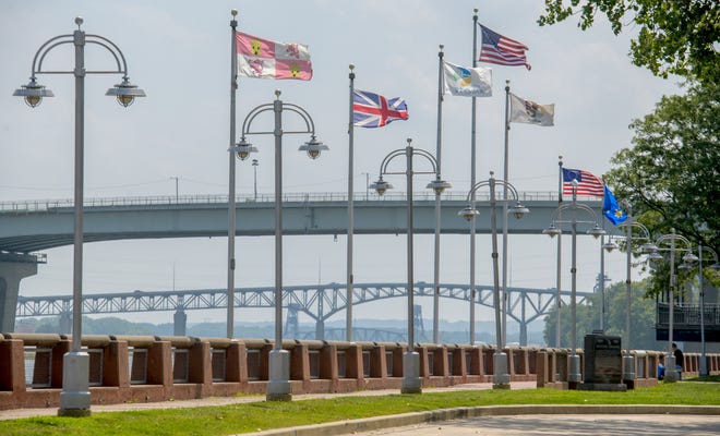 Flags whip in the wind along the Peoria riverfront with the Bob Michel Bridge and the Cedar Street Bridge in the background.