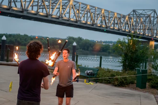 Kyle Wilfinger, left, of East Peoria and Kyle Boyer of Normal keep their eyes on target as they juggle some flaming batons during a weekly gathering of the Heart of Illinois Hoopers on the grounds of the Gateway Building on the Peoria riverfront.