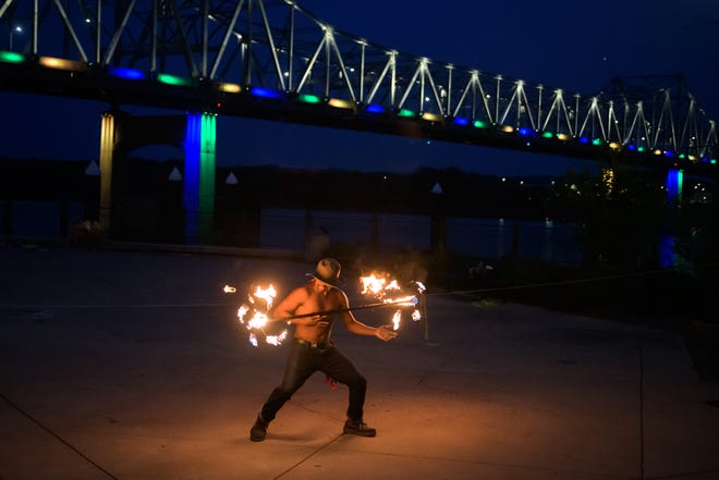 Fire juggler Joshua Kensil spins a flaming staff during a weekly gathering of the Heart of Illinois Hoopers on the grounds of the Gateway Building on Peoria's riverfront.
