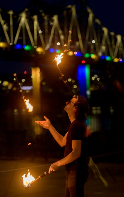 Kyle Wilfinger of East Peoria juggles flaming pins with the lights of the Murray Baker Bridge as a backdrop during the weekly gathering of the Heart of Illinois Hoopers on the grounds of the Gateway Building on Peoria's riverfront.