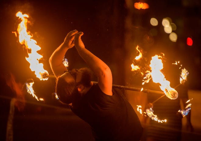 Adrian Boctor of Peoria lets a flaming staff roll down the front of his body as he performs during a weekly gathering of the Heart of Illinois Hoopers on the grounds of the Gateway Building on Peoria's riverfront.