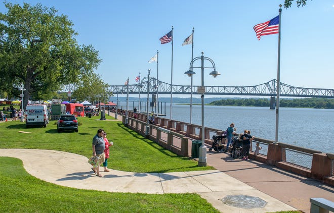 The Murray Baker Bridge stretches across the Illinois River as patrons of the Riverfront Market mill around along the shoreline in Peoria.
