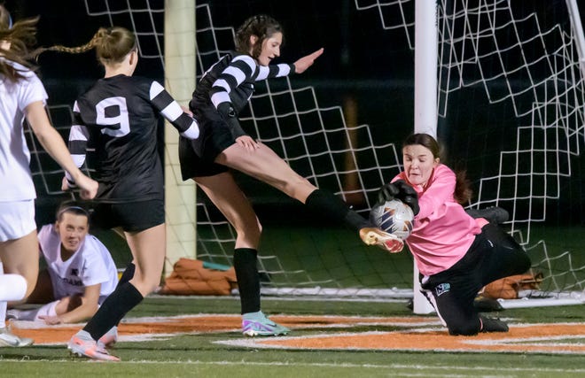 Peoria Notre Dame goalkeeper Sydnee Wharton, right, dives to stop a shot by Washington's Tori Aberle in the second period of their girls soccer match Tuesday, March 19, 2024 in Washington. The Irish defeated the Panthers 2-0.