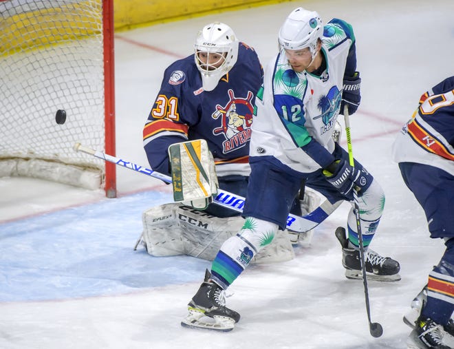 The puck flies past Pensacola's Sean Ross (12) and Peoria goaltender Nick Latinovich, but not into the net, in the third period of Game 2 of the first round of the SPHL playoffs Saturday, April 13, 2024 at the Peoria Civic Center. The Rivermen advanced to the semifinals with a 6-1 victory.
