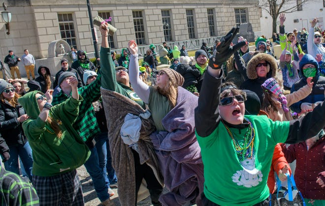 A reveler catches a T-shirt thrown from a float as others scream for more during the annual St. Patrick's Day Parade on Friday, March 17, 2023 in downtown Peoria.
